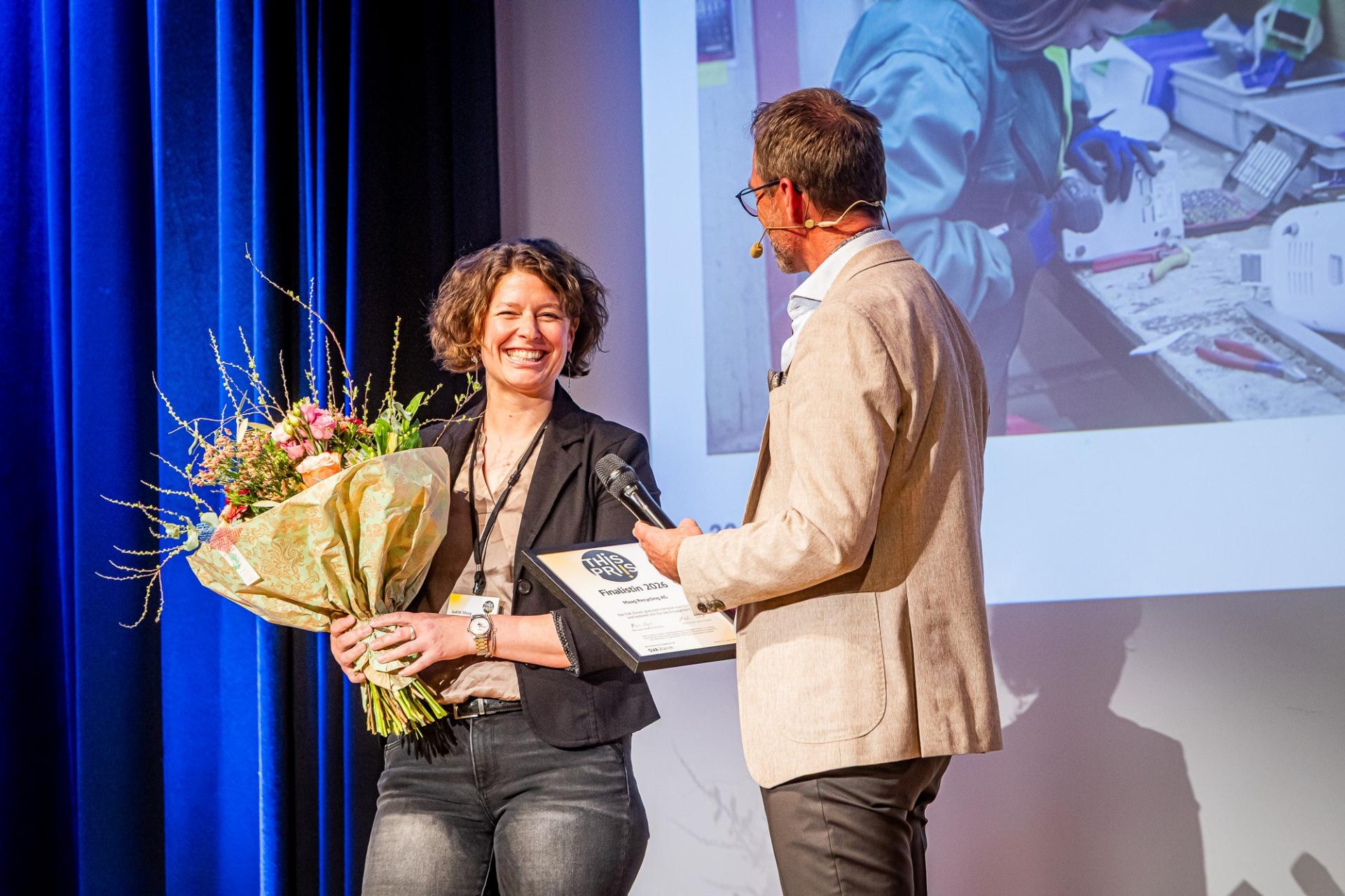 Das Bild zeig Martin Schilt im Interview mit Judith Maag, Inhaberin und Geschäfts¬führerin der Maag Recycling AG.. Sie hält einen grossen Blumenstrauss.