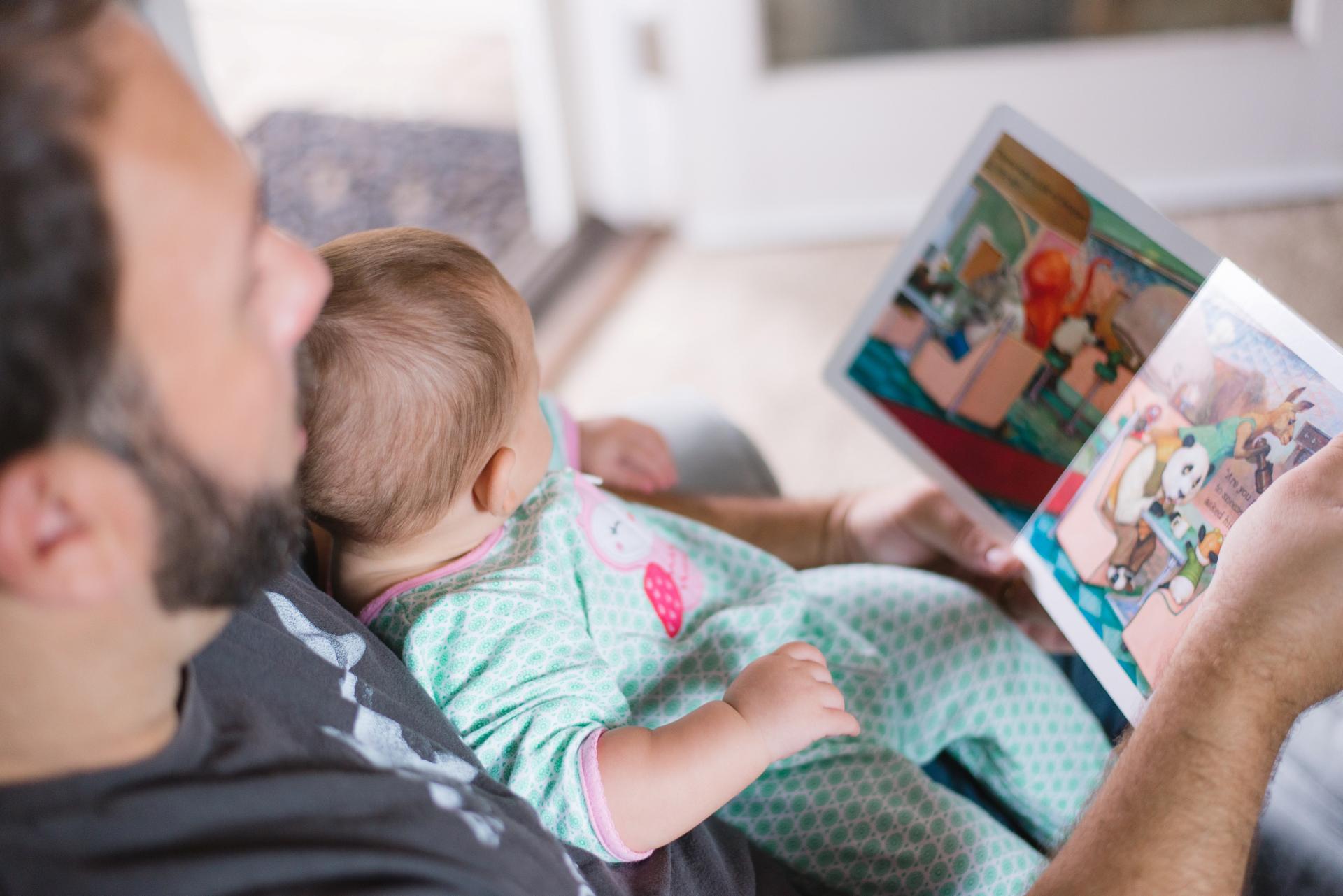 Ein Vater schaut mit seinem Kind ein Bilderbuch an.