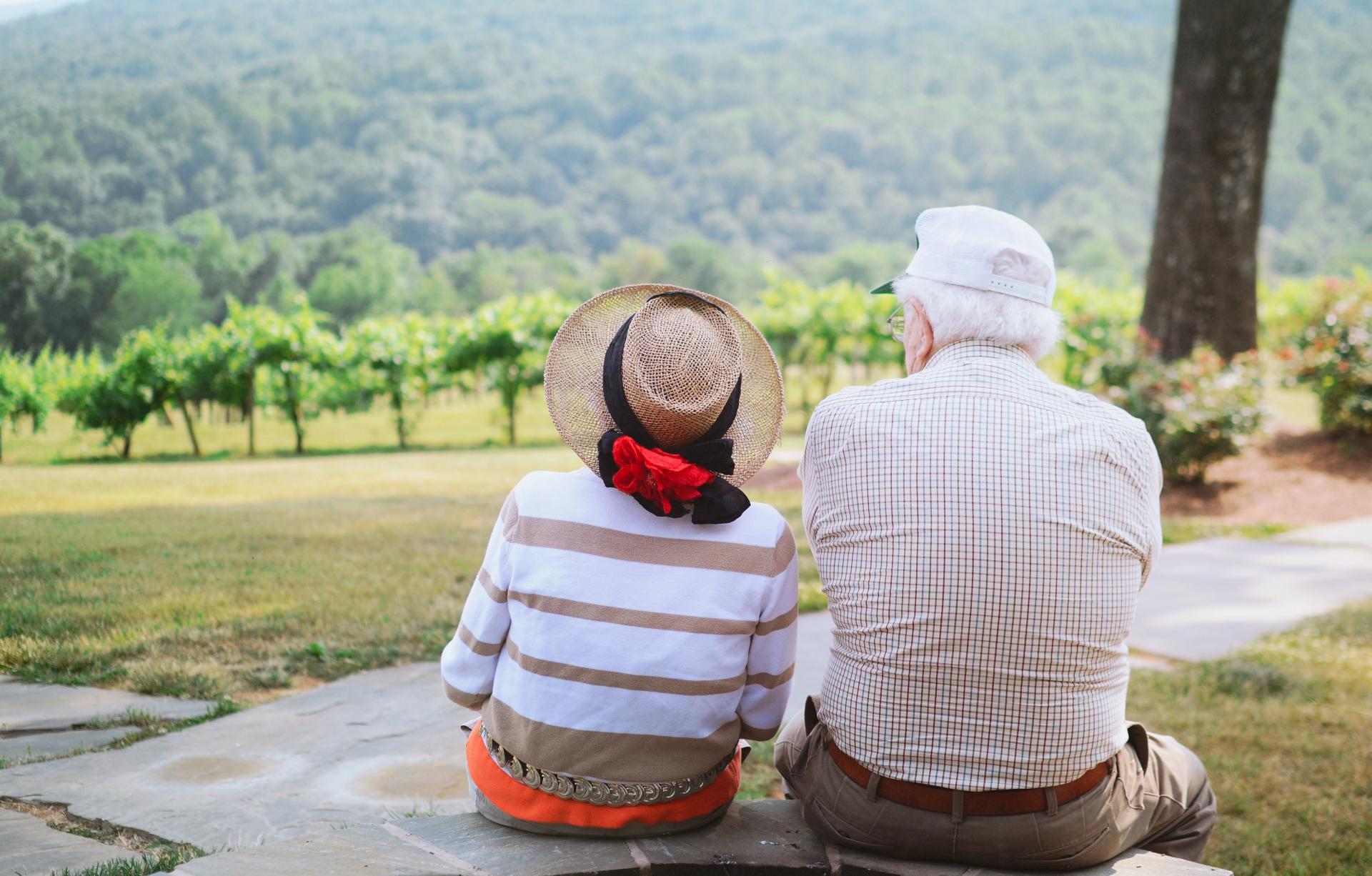 Ein älteres Paar sitzt im Freien und schaut in die Ferne