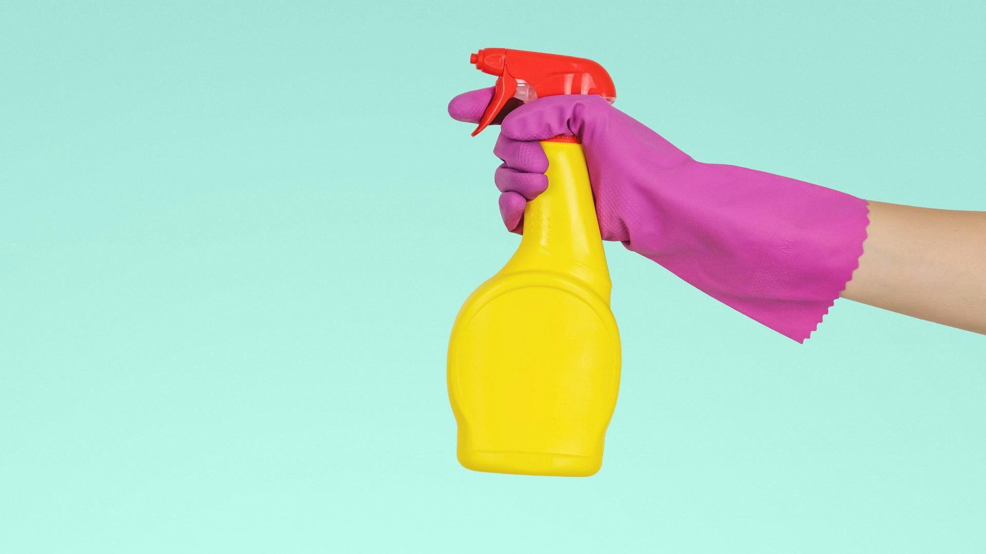 Eine Hand mit einer Putzmittelsprühflasche