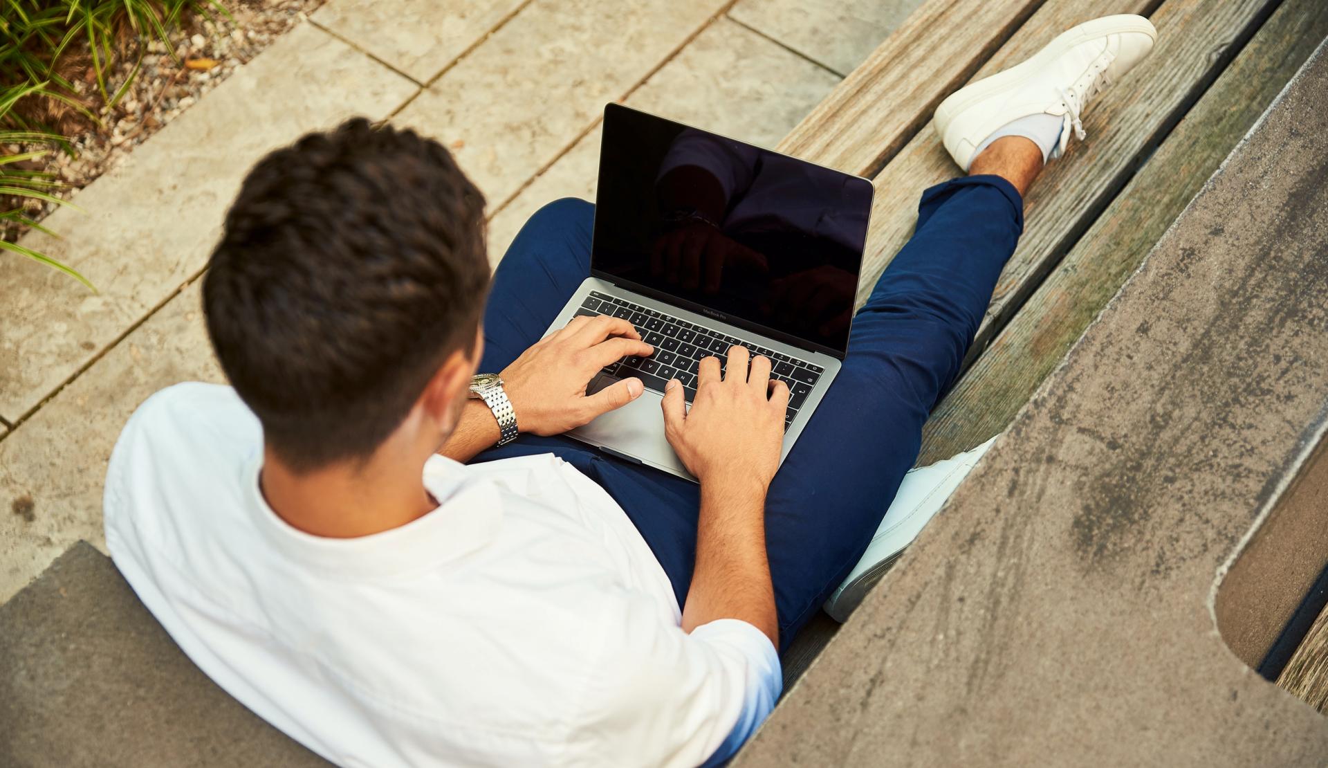 Student arbeitet im Freien am Laptop.