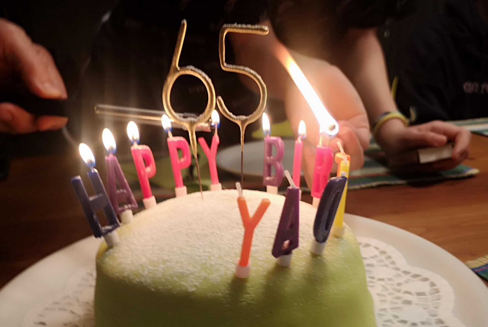 Auf einer Torte zum 65. Geburtstag werden die Kerzen angezündet.
